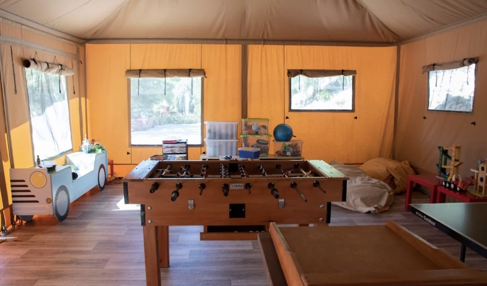 Indoor game room with foosball table, colorful toys, and windows letting in natural light.