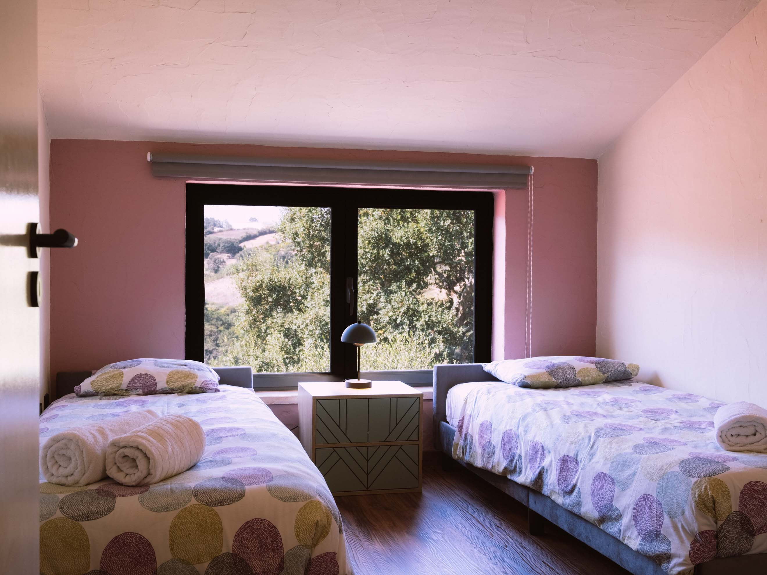 Twin beds with polka dot bedding and rolled towels, separated by small bedside table with lamp.