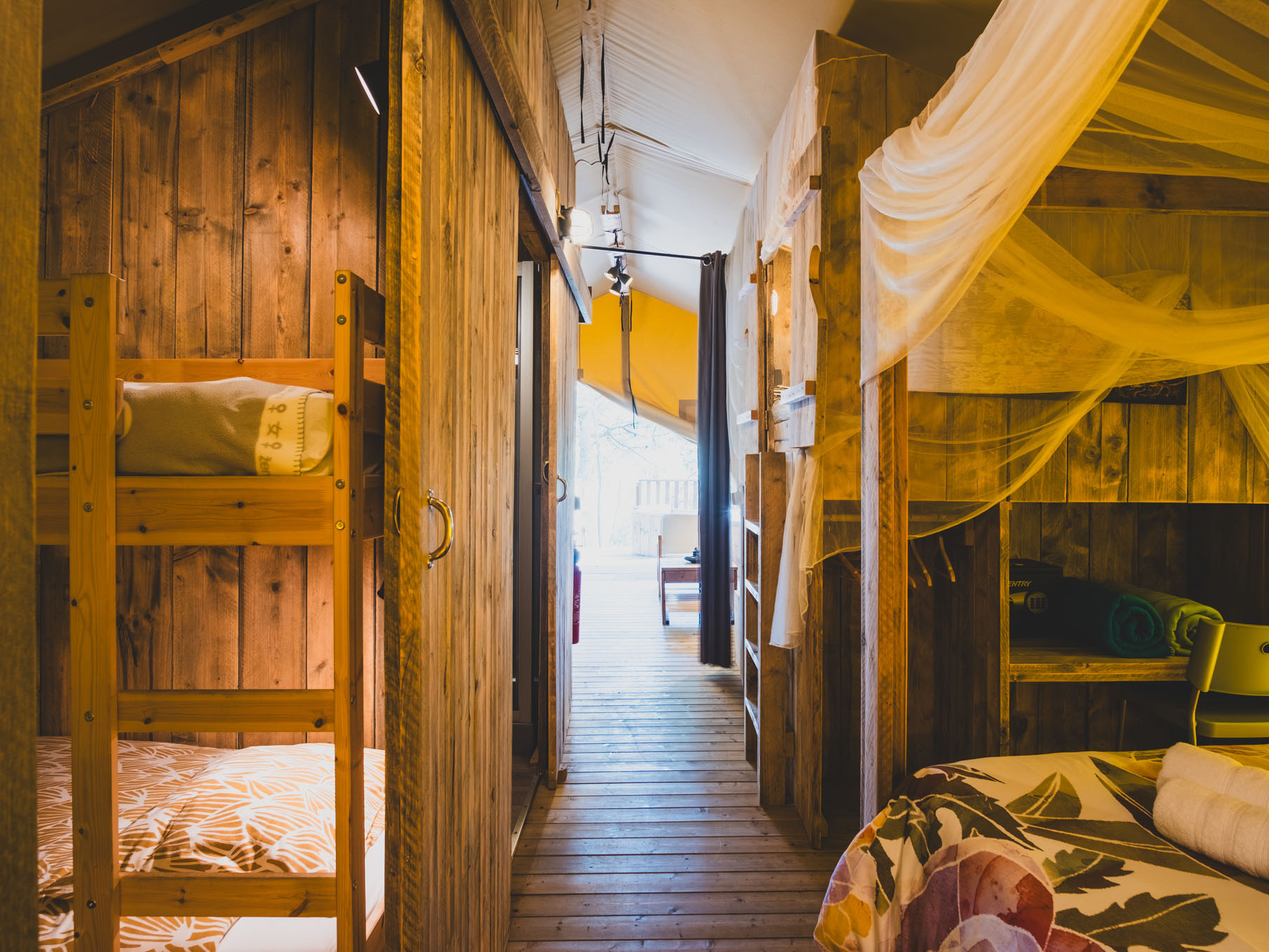 Wood-paneled interior with bunk beds, a walkway leading to a seating area with natural light